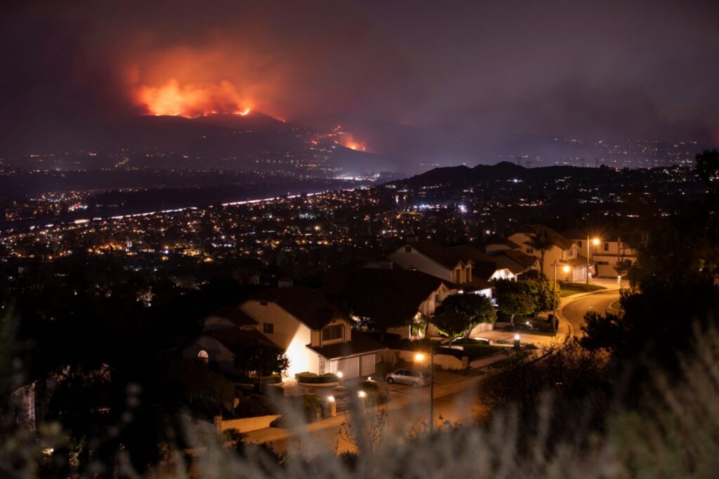 Suburban neighborhood threatened by wildfire at night — wildfire home protection can make the difference