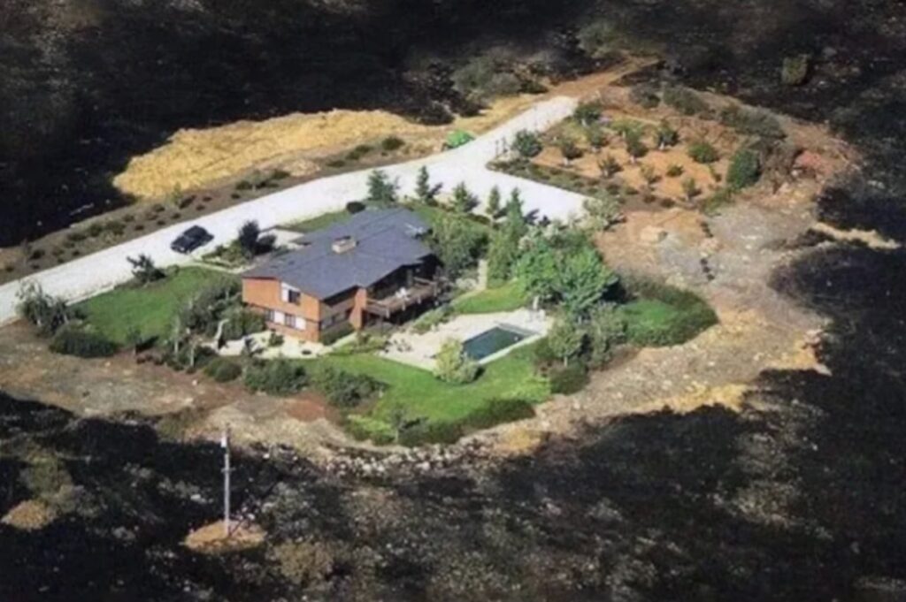 A well-maintained property with defensible space survives untouched while the surrounding land is burned.